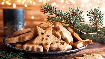1180203969 Leckere hausgemachte Weihnachtsplätzchen mit festlichen goldenen Lichtern